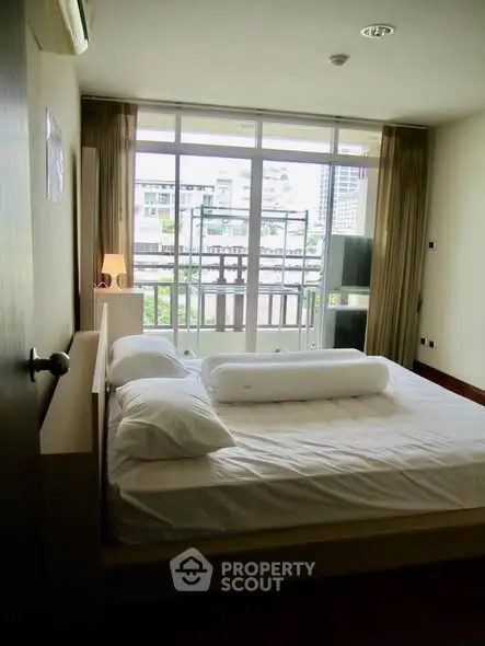 Spacious bedroom with large windows and city view, featuring modern decor and ample natural light.