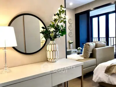 Elegant bedroom with modern decor, featuring a stylish mirror and cozy seating area.