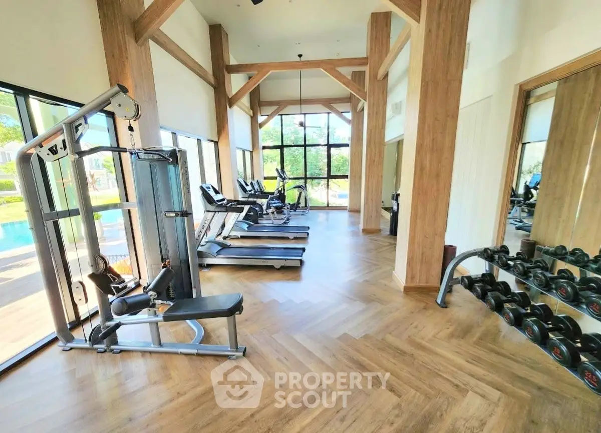 Spacious gym with modern equipment and pool view in luxury real estate property.