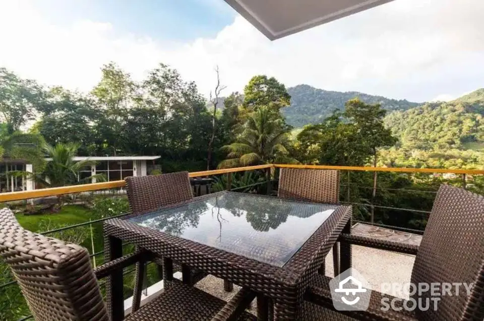 Stunning balcony with outdoor dining set and lush green mountain views.