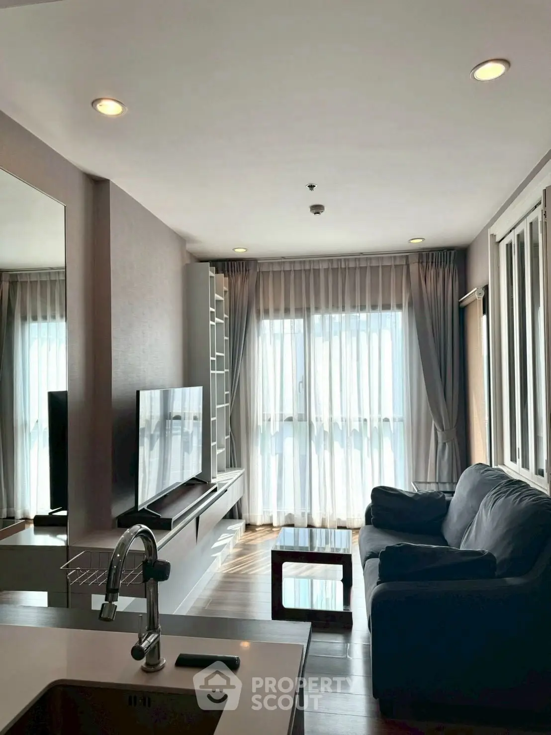 Modern living room with sleek furniture and large window, perfect for relaxation.