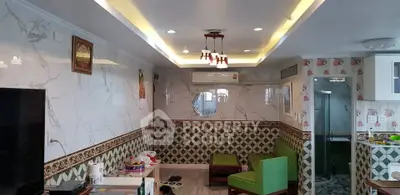 Spacious living room with elegant decor and modern lighting, featuring a cozy seating area and stylish wall patterns.