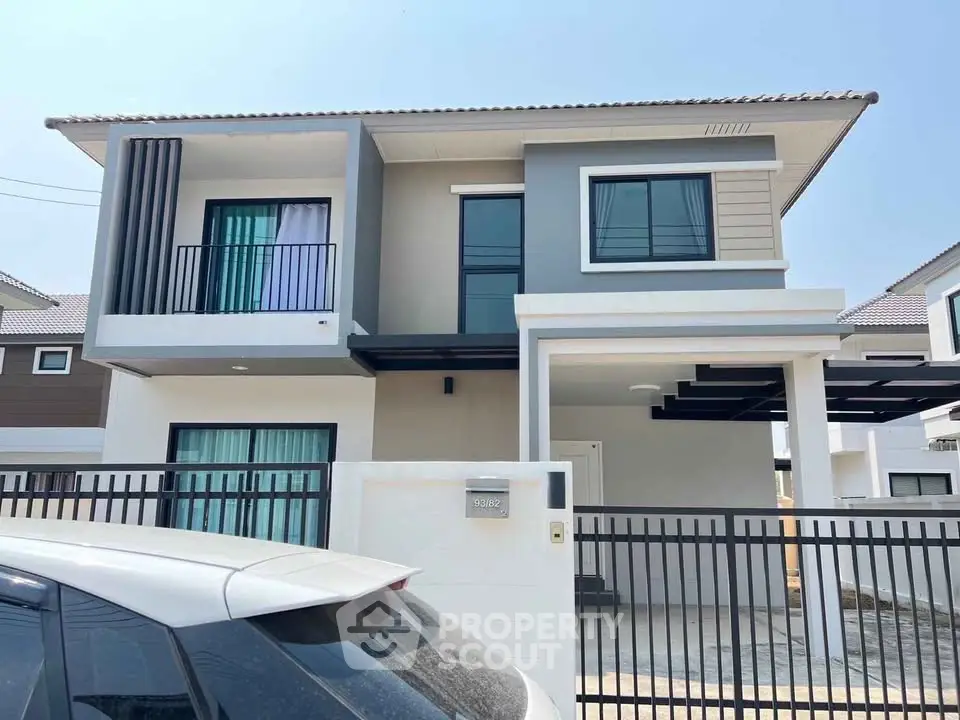 Modern two-story house with sleek design and gated entrance in suburban neighborhood.