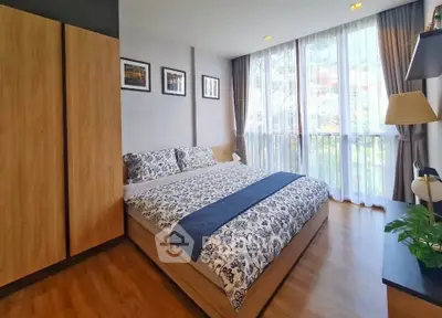Charming bedroom with large windows and stylish decor, perfect for relaxation and comfort.
