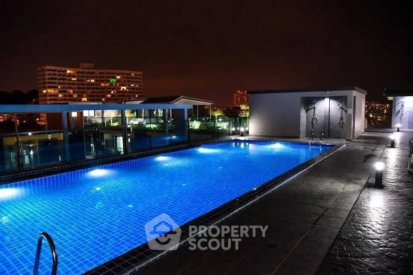 Stunning rooftop pool with city skyline view at night, perfect for relaxation and entertainment.