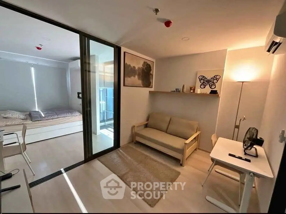 Modern studio apartment with cozy living area and bedroom, featuring sleek furniture and natural light.