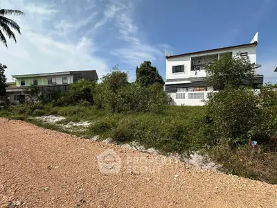 Spacious plot with potential for development, featuring nearby residential buildings and lush greenery.