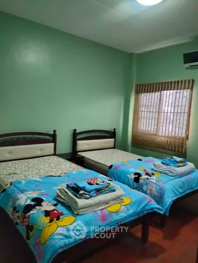 Cozy bedroom with twin beds and playful Mickey Mouse bedding, perfect for a child's room.