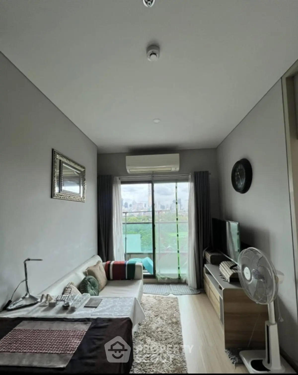 Modern living room with large window and city view, stylish decor and cozy atmosphere.