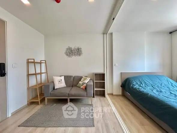 Modern studio apartment with cozy living area and bed, featuring minimalist decor and wooden flooring.