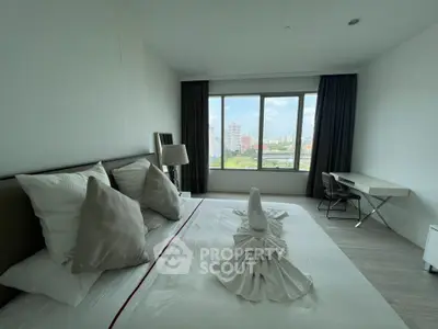 Spacious bedroom with city view and modern furnishings in a high-rise apartment.