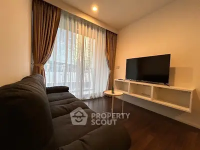 Cozy living room with modern sofa and large TV, featuring floor-to-ceiling windows and elegant curtains.