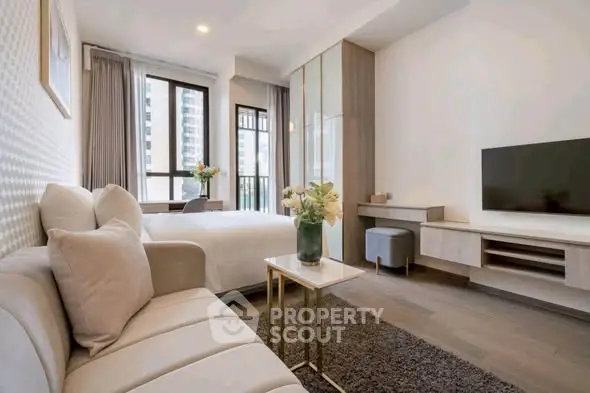Modern studio apartment with stylish decor, featuring a cozy living area and large windows for natural light.