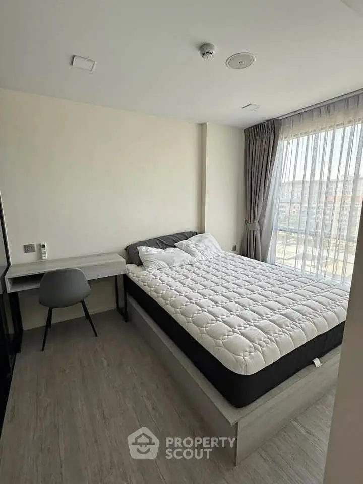 Modern bedroom with large window and stylish furnishings in a high-rise apartment.