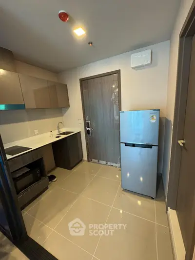 Modern kitchen with sleek cabinets and stainless steel fridge in a compact layout.