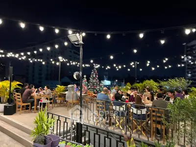 Charming rooftop dining area with festive lighting and city views, perfect for social gatherings.