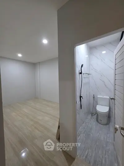 Modern bathroom with sleek design and adjacent empty room, ideal for customization.