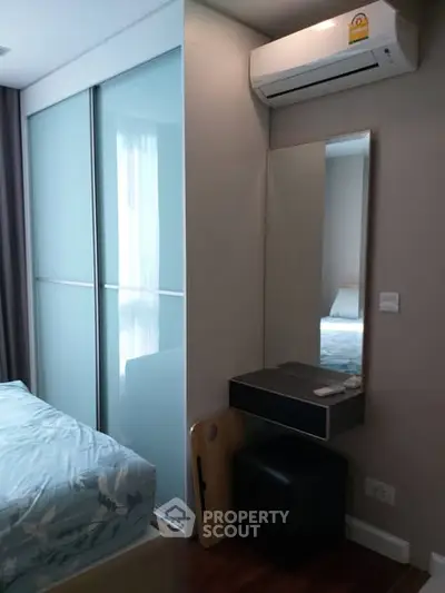 Modern bedroom with sliding closet doors and air conditioning unit.