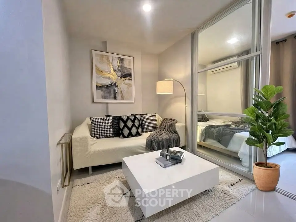 Modern living room with cozy decor and stylish furniture, featuring a large mirror and elegant lighting.