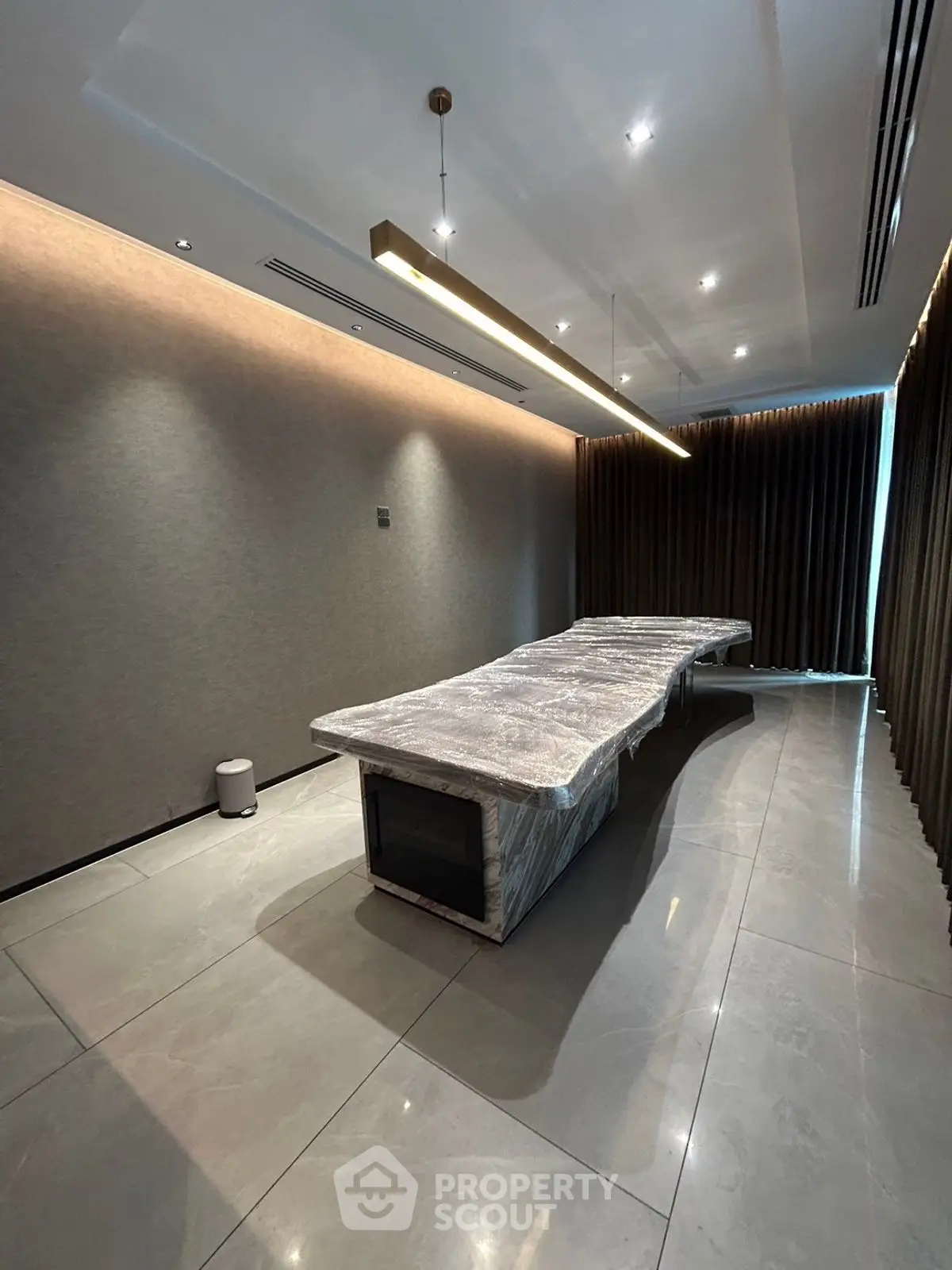 Luxurious modern room with elegant lighting and large covered table, perfect for meetings or dining.