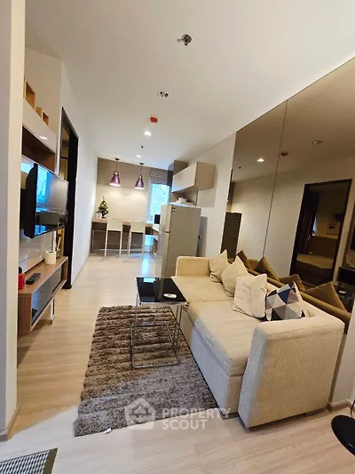 Modern living room with cozy beige sofa, stylish decor, and open kitchen layout in a contemporary apartment.