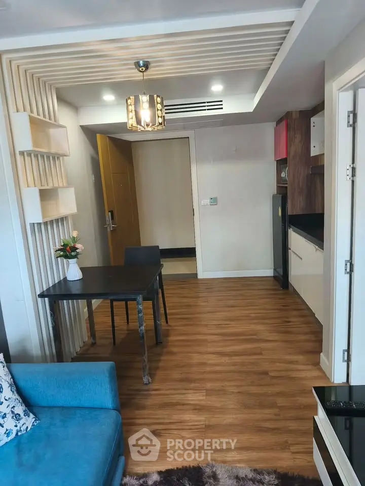 Modern living room with stylish decor and open kitchen layout, featuring wooden flooring and elegant lighting.