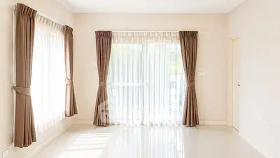 Spacious empty room with large windows and elegant curtains, perfect for customization.