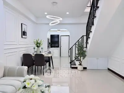 Elegant modern living room with dining area and staircase, featuring sleek design and stylish decor.