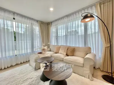 Elegant living room with cozy sofa, stylish floor lamp, and large windows with sheer curtains.