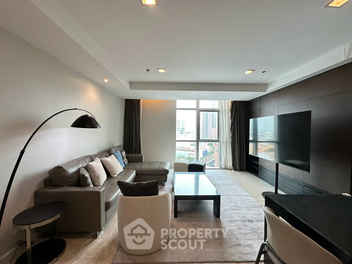 Spacious modern living room with large windows and city view, featuring stylish furniture and contemporary decor.