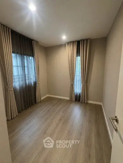Spacious empty room with elegant curtains and wooden flooring, perfect for customization.