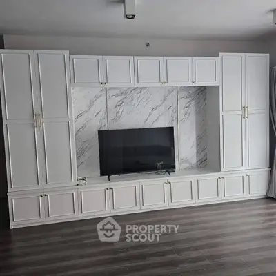 Modern living room with elegant built-in white cabinetry and sleek marble TV backdrop.