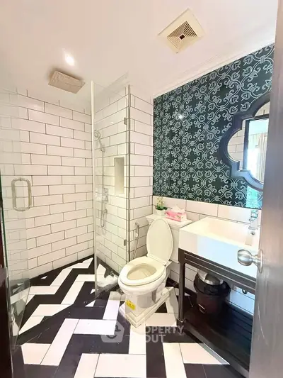 Stylish bathroom with modern design, featuring a glass shower, patterned tiles, and elegant fixtures.