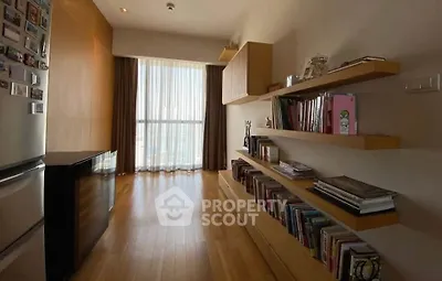 Stylish apartment with wooden flooring and built-in bookshelves, featuring a bright window view.
