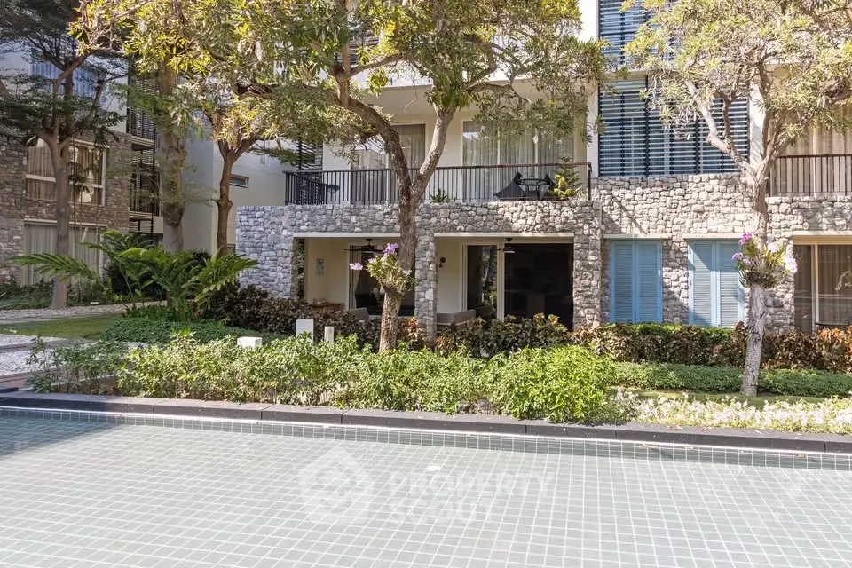 Luxurious apartment building with lush garden and serene pool view.