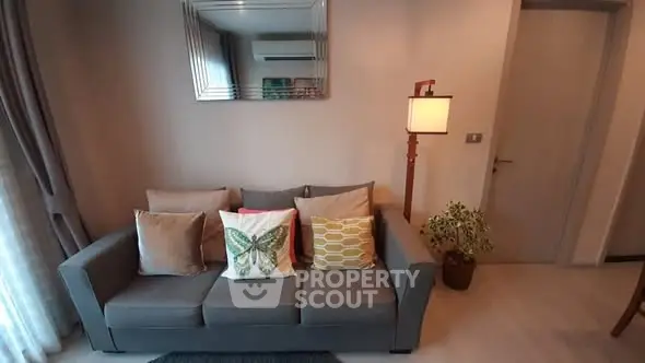 Modern living room with stylish sofa and decorative pillows, featuring a chic mirror and ambient lighting.