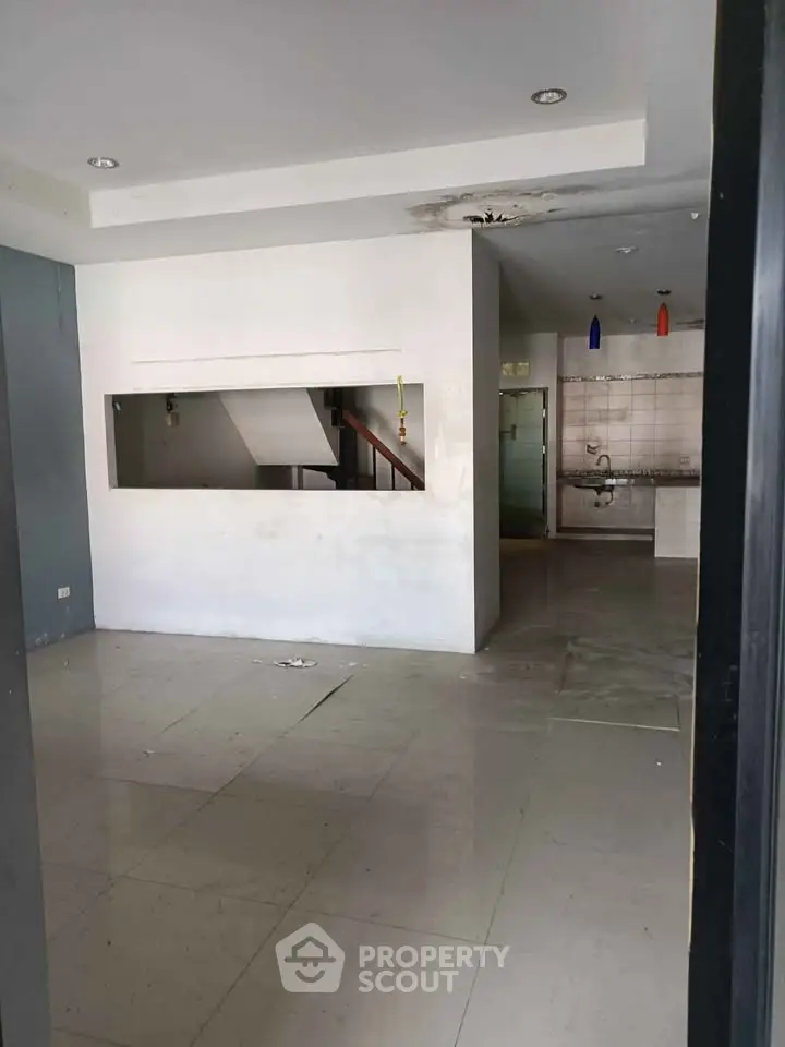 Spacious open-plan living area with modern kitchen and staircase view.