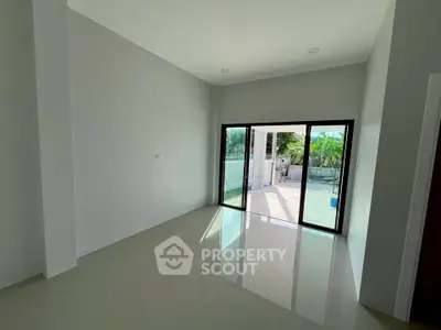 Spacious empty room with large sliding glass doors leading to a sunny patio.