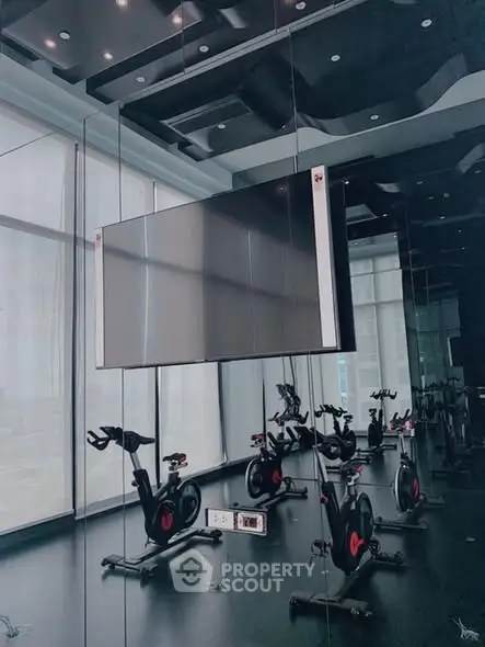Modern gym with exercise bikes and large TV in luxury building