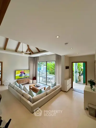 Spacious living room with modern decor and large windows opening to a lush garden view.
