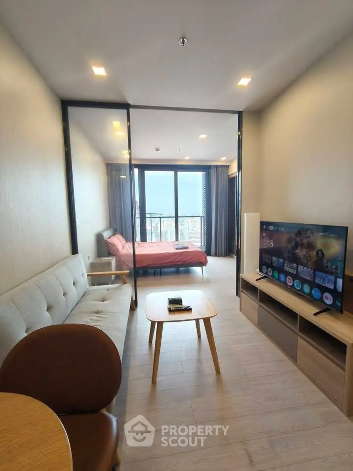 Modern open-layout living room with TV and bedroom view in high-rise apartment