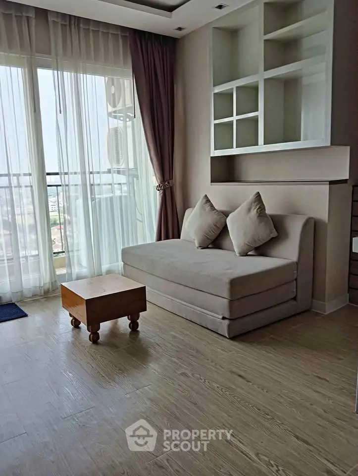 Modern living room with large windows and cozy seating area in a stylish apartment.