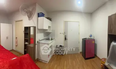 Cozy studio apartment with compact kitchen and vibrant red bedding