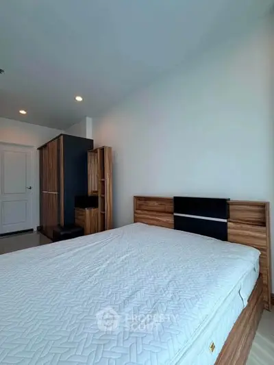 Spacious bedroom with modern wooden furniture and ample natural light.