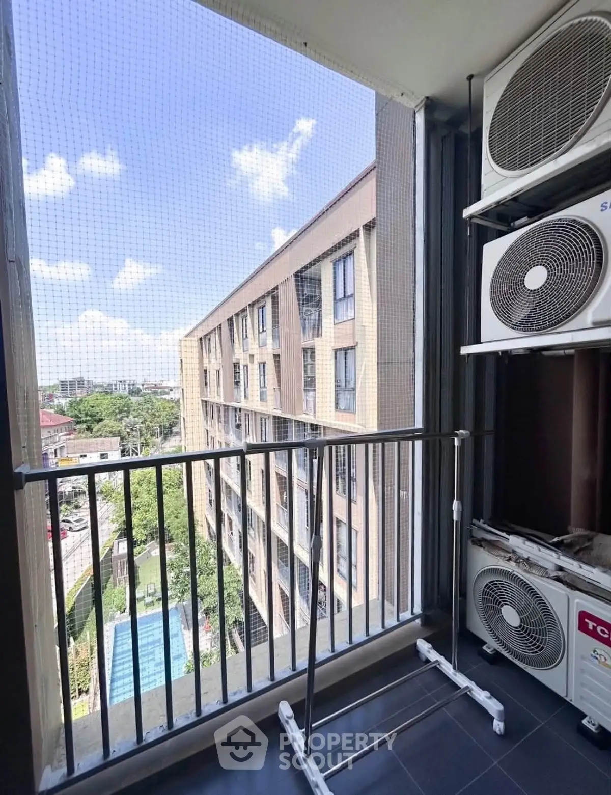 Modern apartment balcony with air conditioning units and city view.