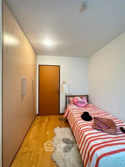 Cozy bedroom with single bed, wooden wardrobe, and stylish decor in modern apartment.