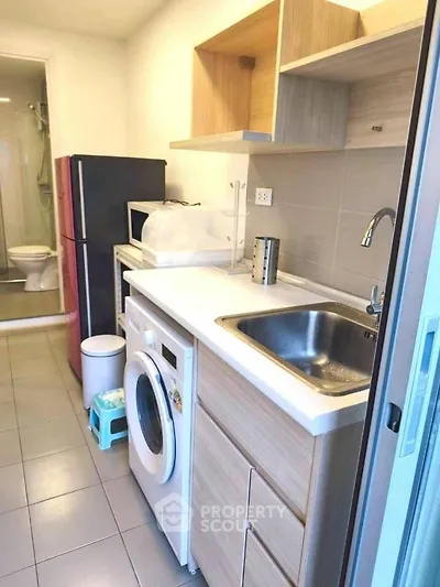 Compact kitchen with washing machine and modern appliances in cozy apartment.