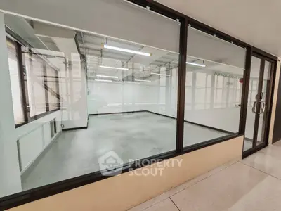 Spacious commercial office space with large glass windows and modern lighting.