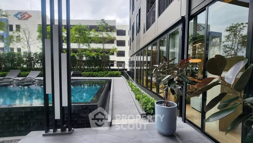 Modern apartment complex with pool and lush greenery, offering a serene urban oasis.