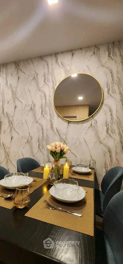 Elegant dining room with marble accent wall and round mirror, featuring a stylish table setting and ambient lighting.